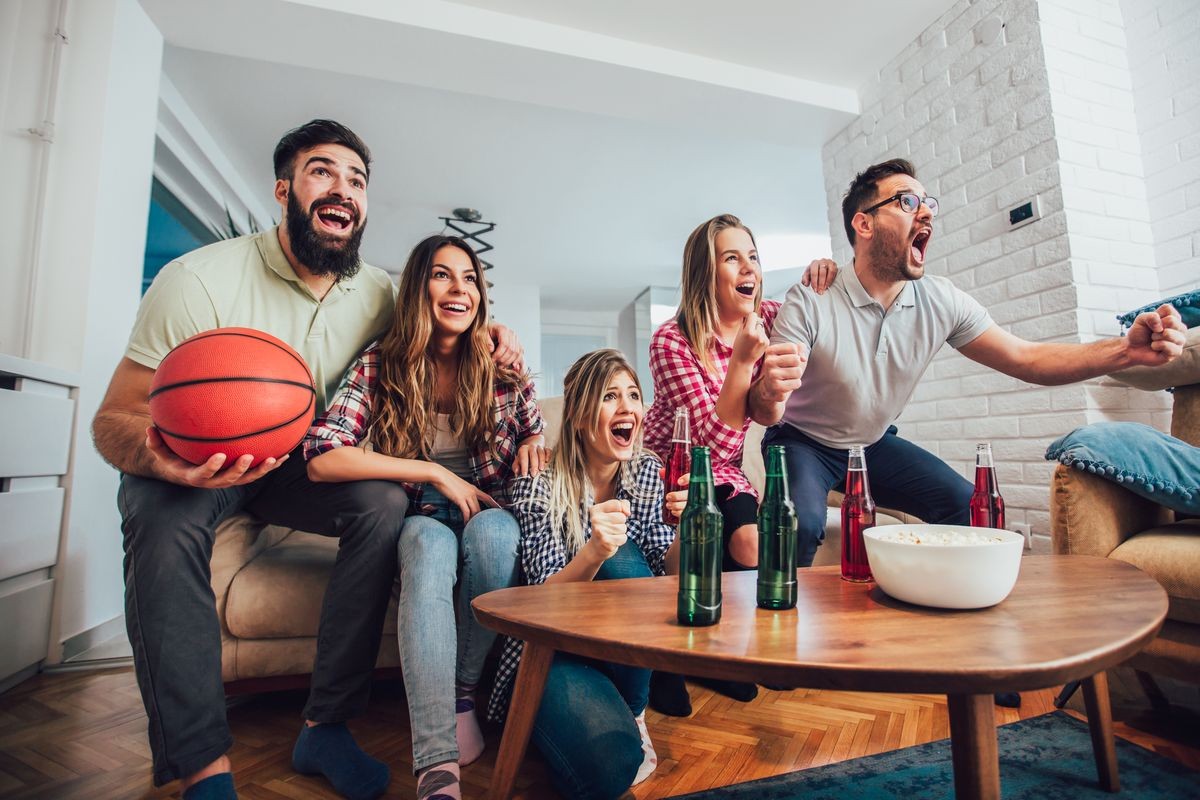 Happy friends or basketball fans watching basketball game on tv and celebrating victory at home.Friendship, sports and entertainment concept.