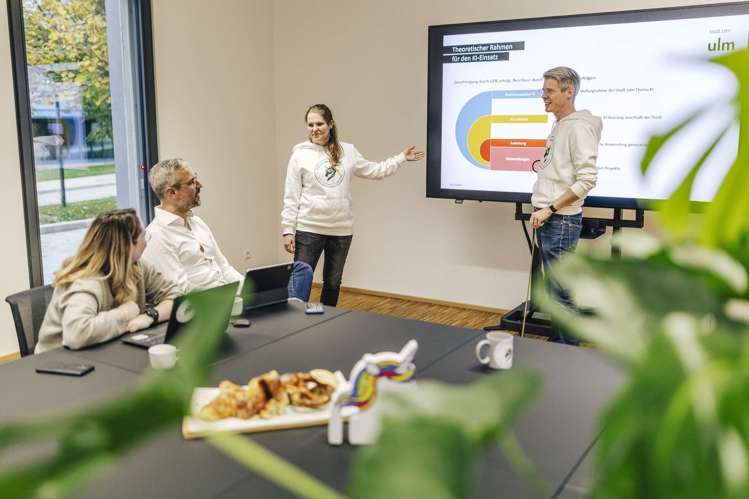Team in Besprechung bei Youniquehorns praesentiert auf einem Bildschirm.